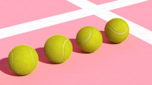 three tennis balls lined up on a pink surface