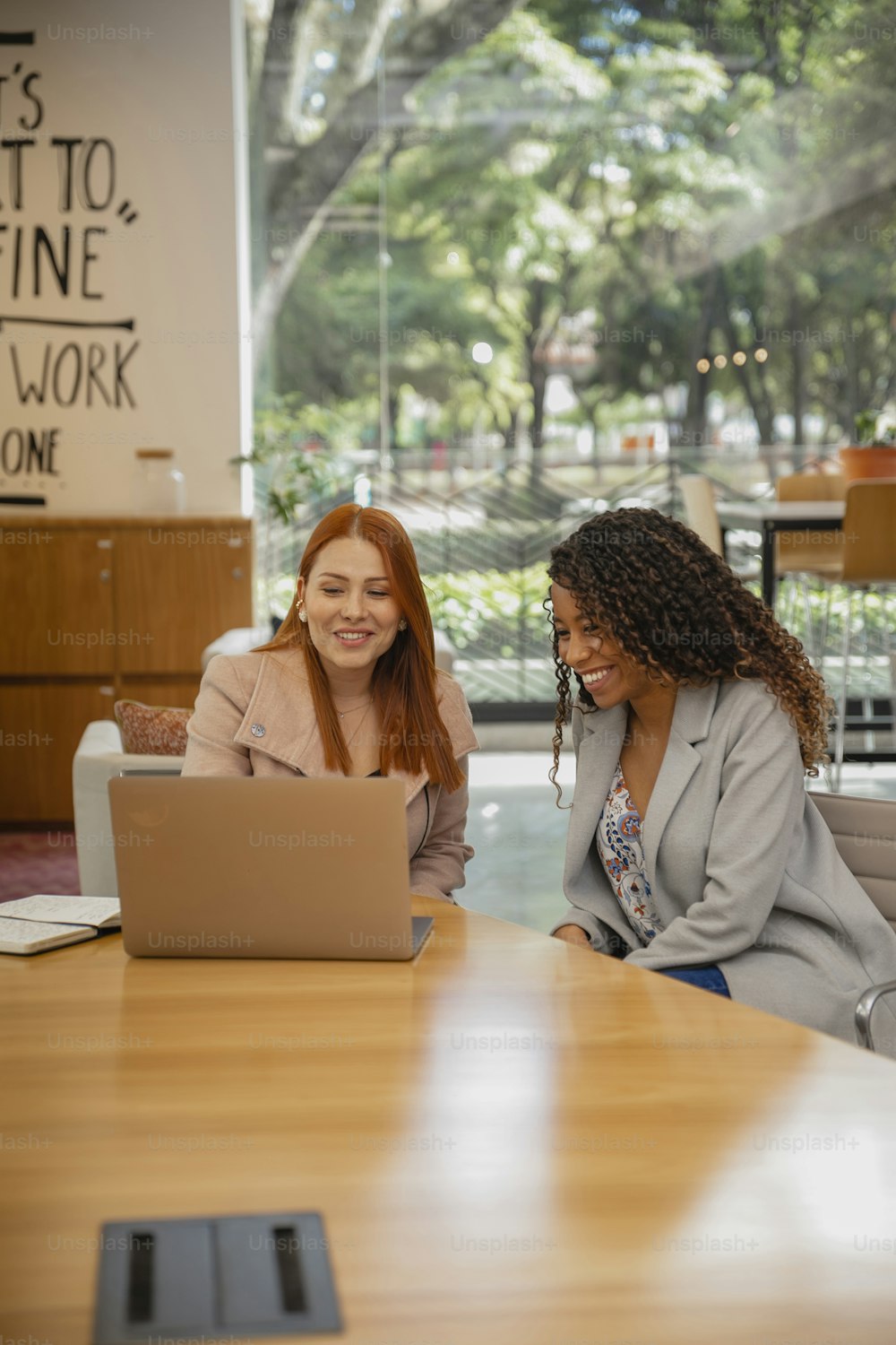 two women sitting at a table with a laptop