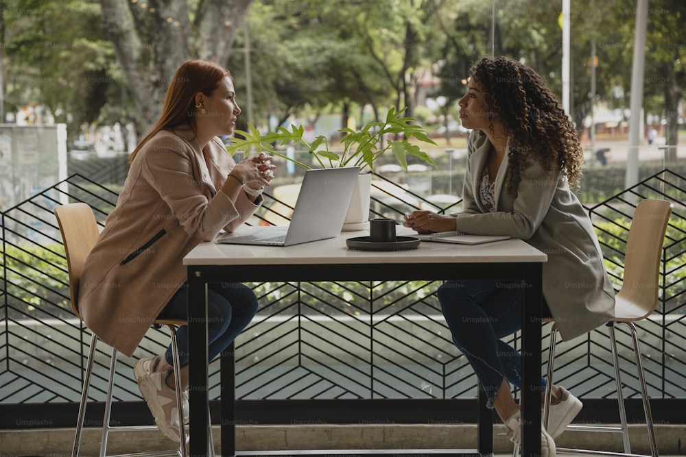 Dos mujeres sentadas en una mesa hablando entre sí