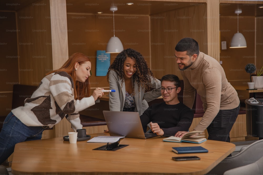 a group of people standing around a table with a laptop