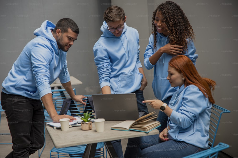 a group of people standing around a table with a laptop