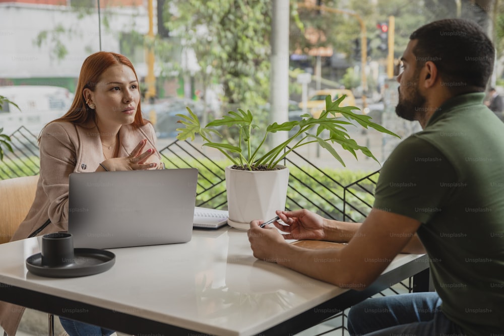 a man and a woman sitting at a table with a laptop