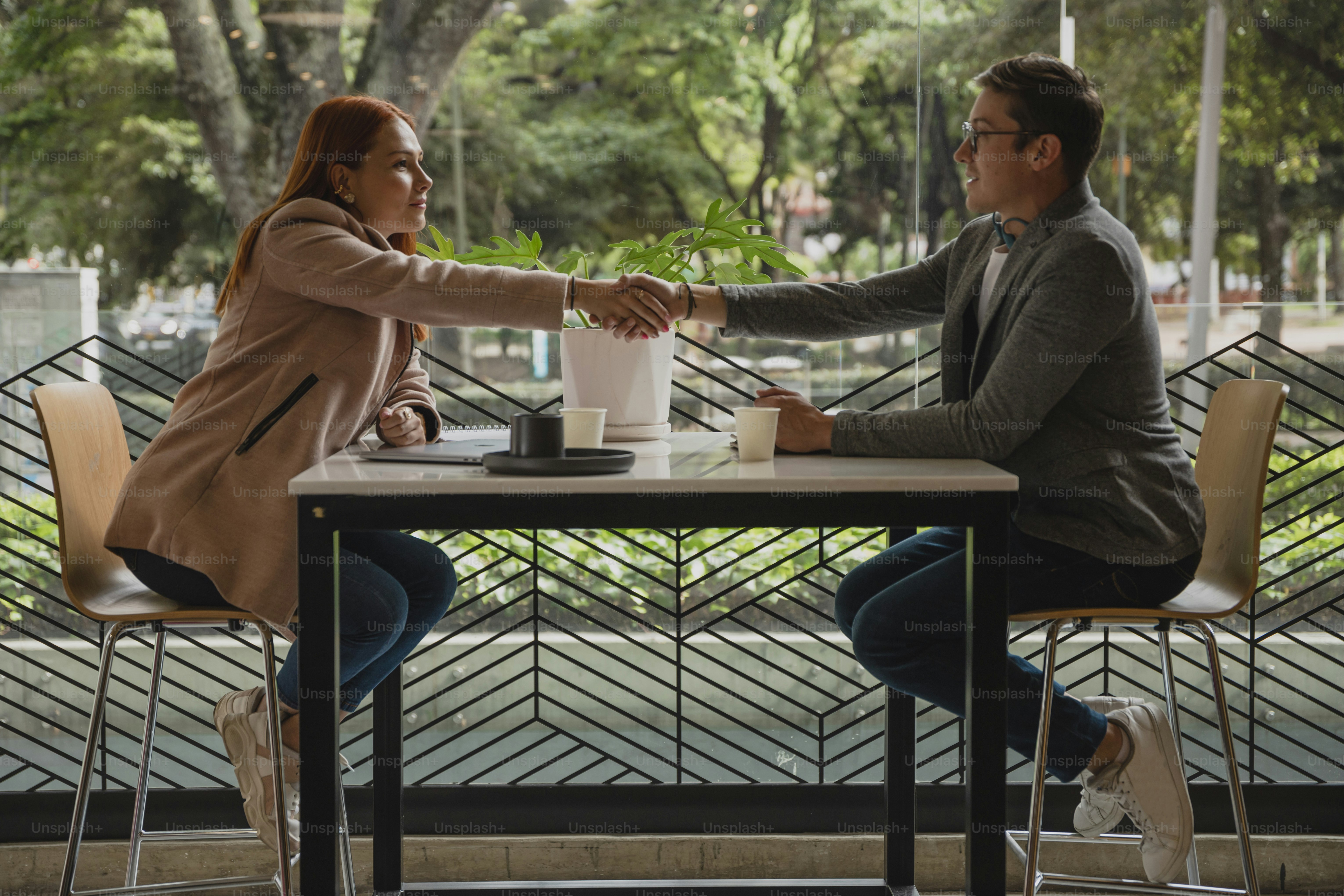 a man and a woman sitting at a table shaking hands