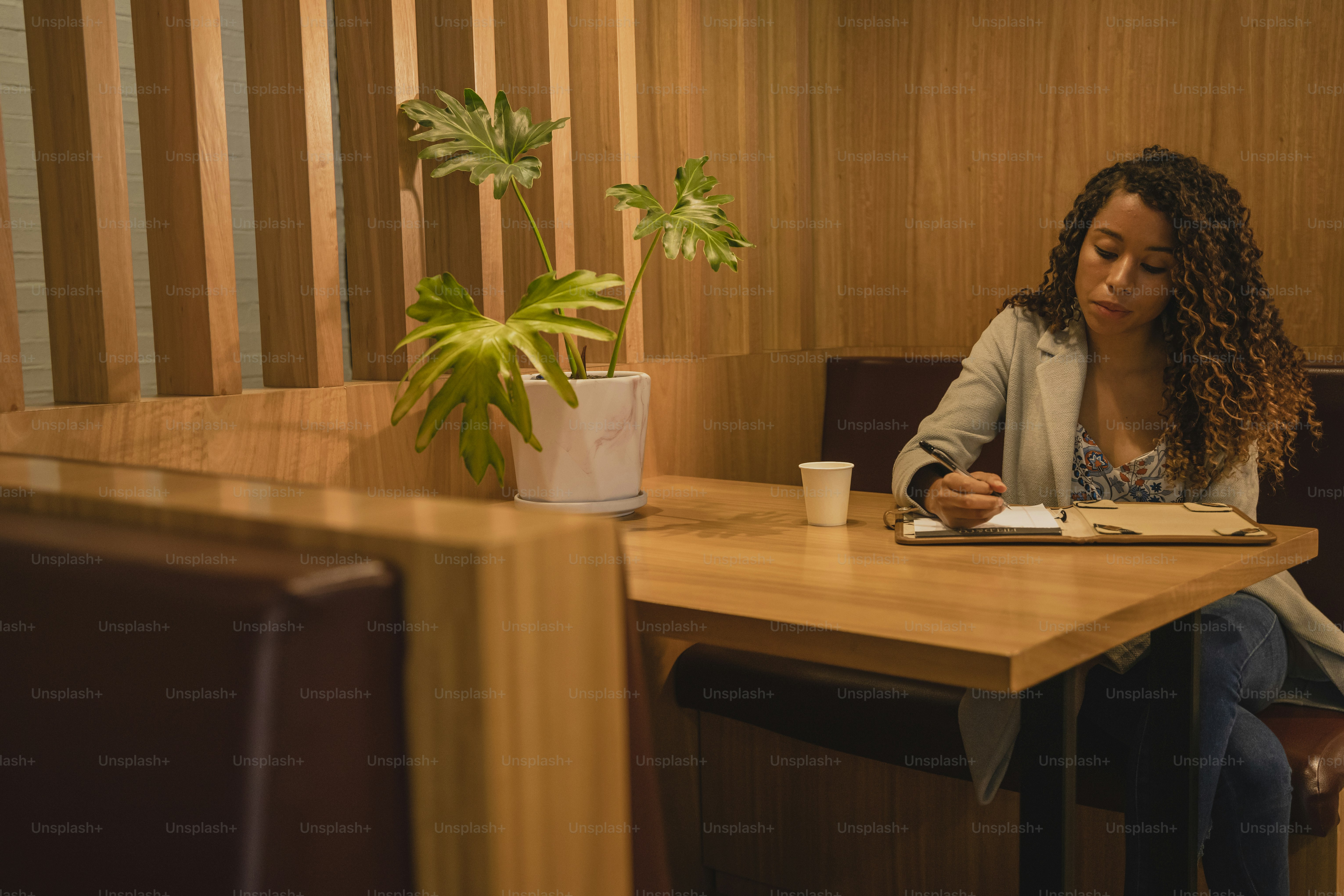 a woman sitting at a table with a book and a plant