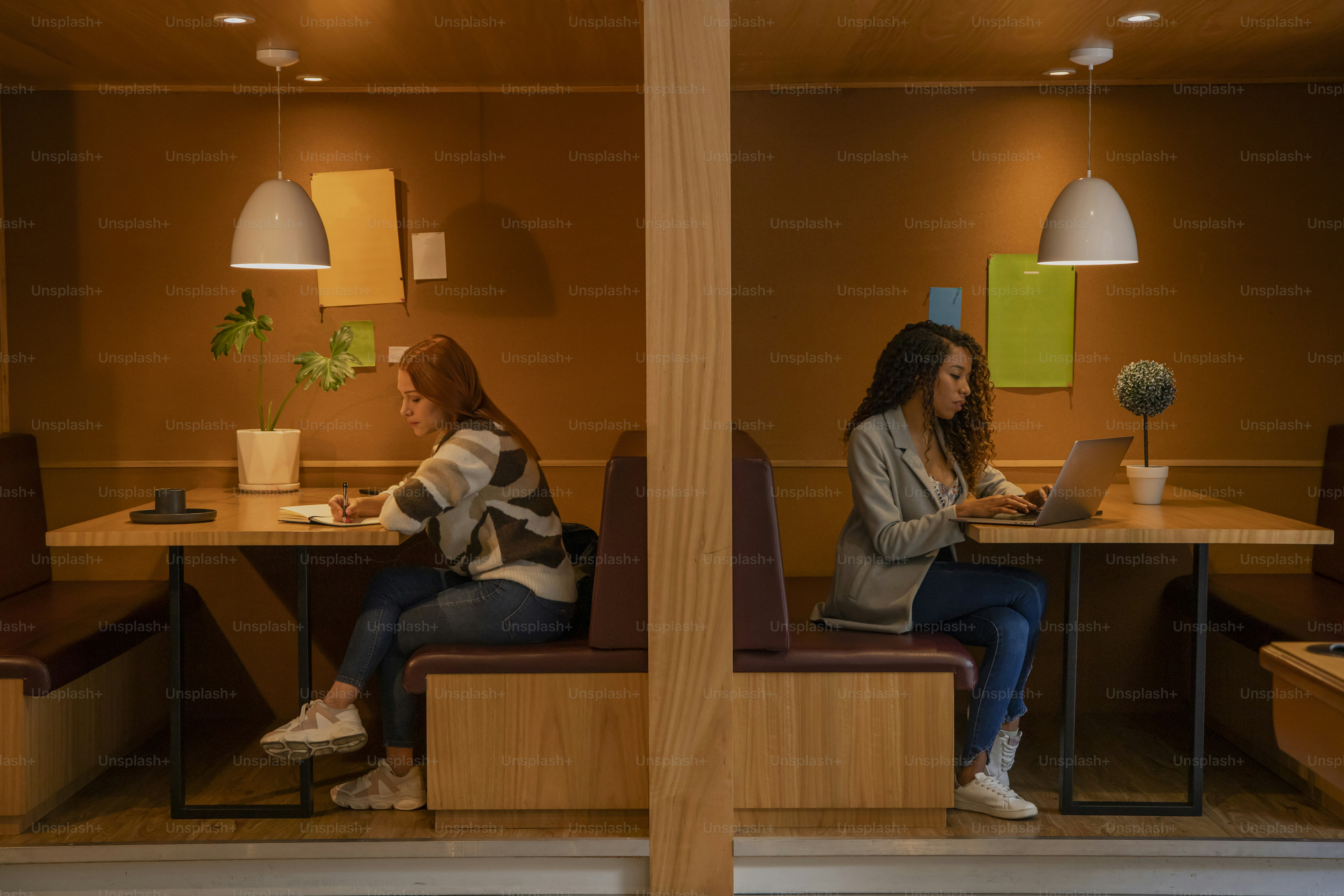 duas mulheres sentadas em uma mesa com laptops