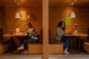 two women sitting at a table with laptops