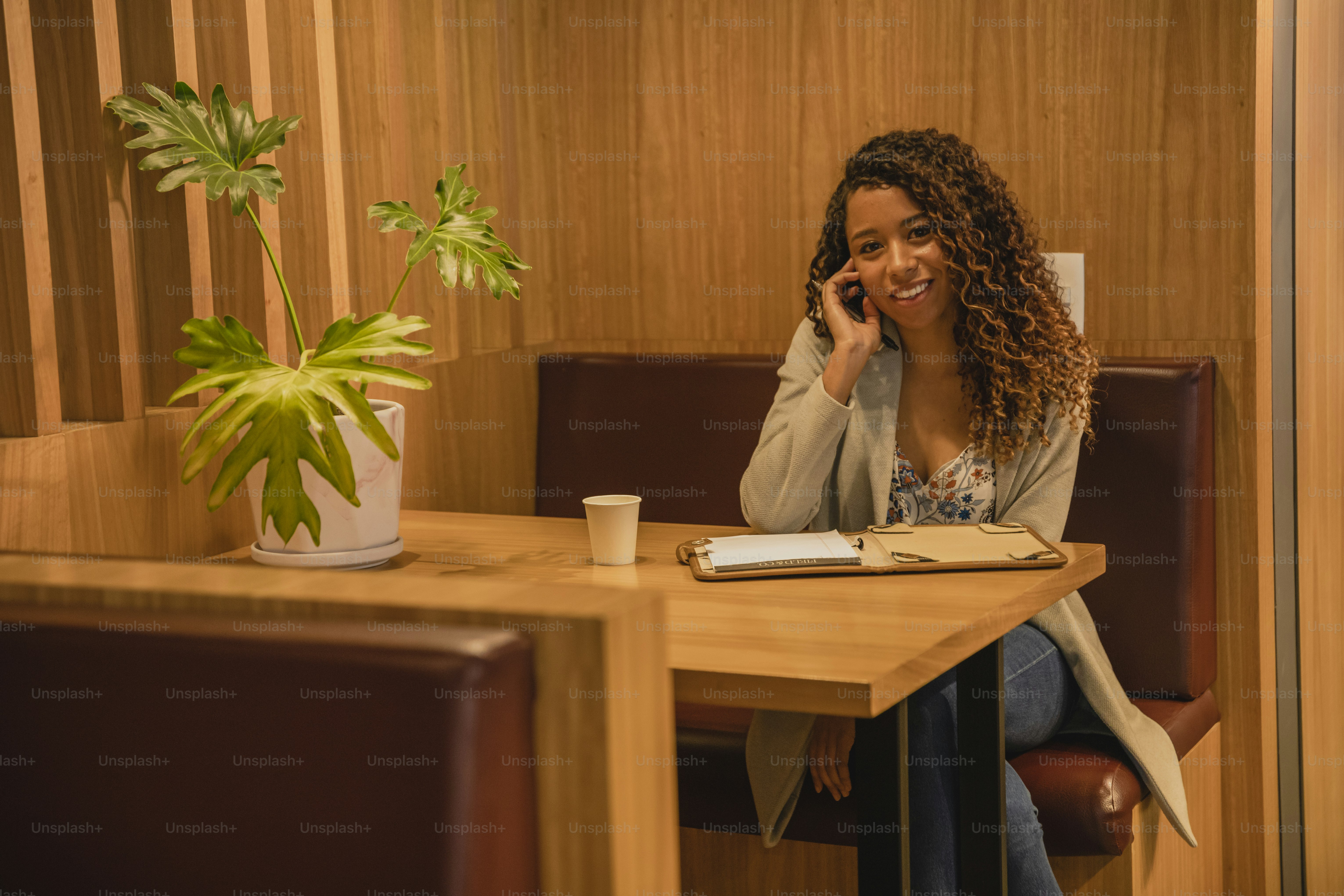 a woman sitting at a table talking on a cell phone