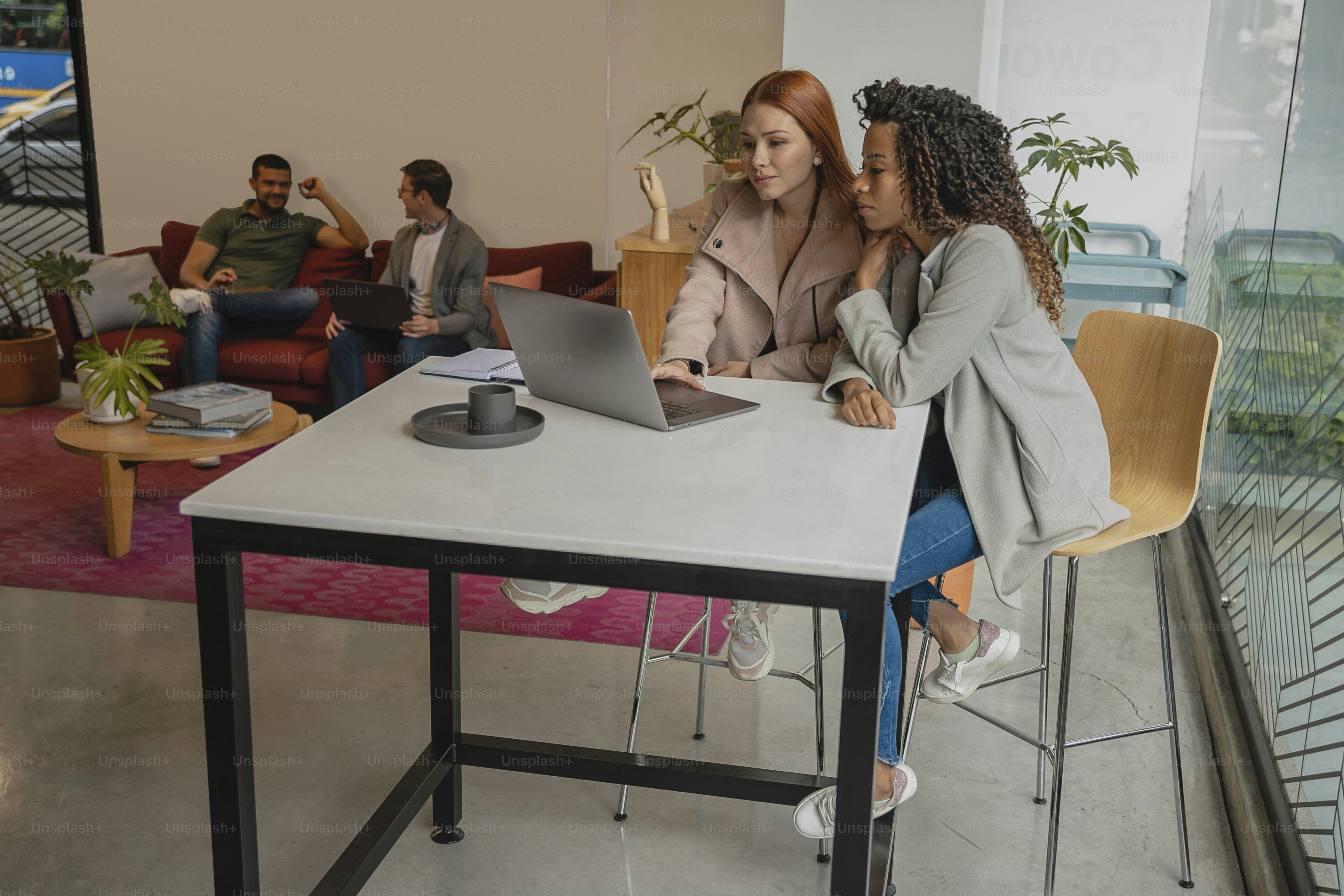 Zwei Frauen sitzen mit einem Laptop an einem Tisch