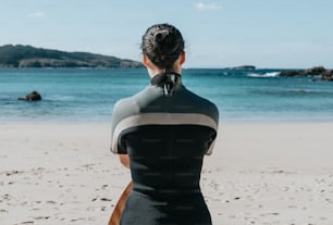 Una donna in una muta che si siede su una spiaggia