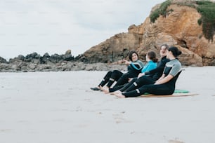 a group of people sitting on top of a surfboard on a beach