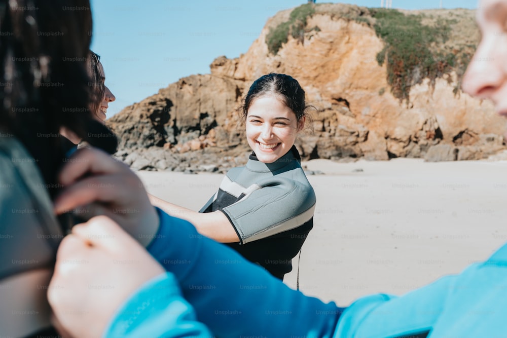 a woman smiles as she adjusts another woman's wetsuit