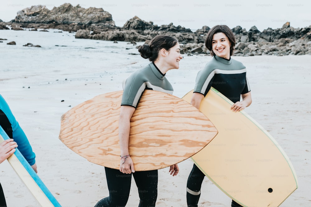 a group of women walking along a beach holding surfboards
