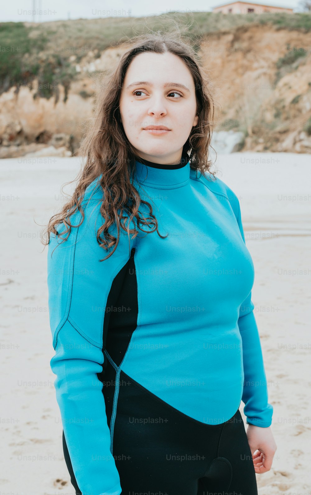 a woman standing on a beach in a wet suit