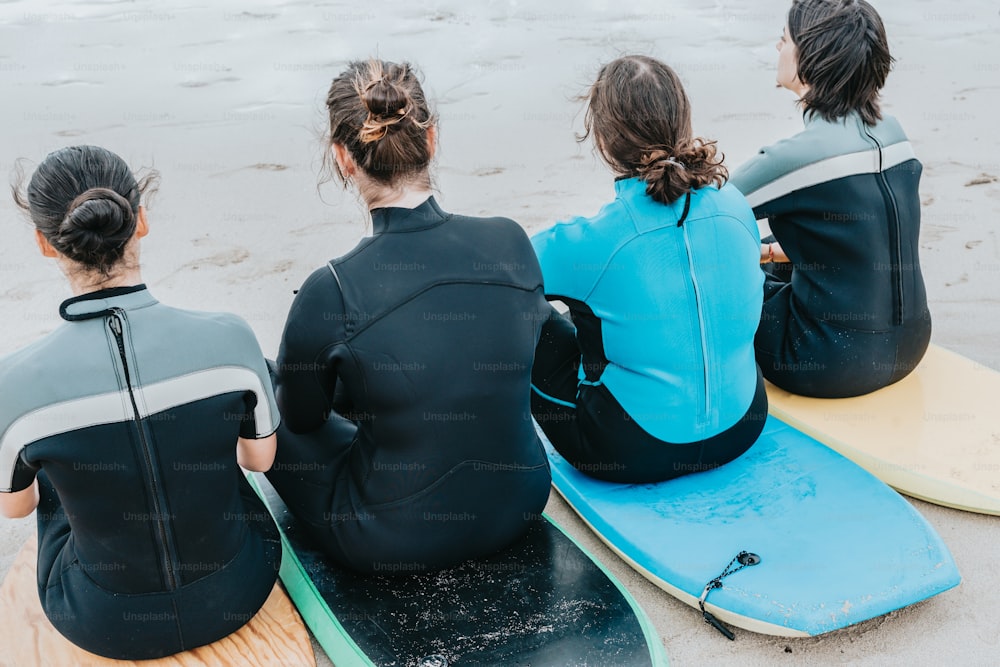a group of three women sitting on top of surfboards