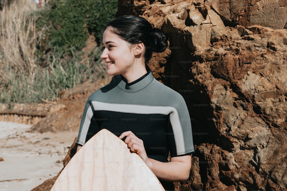 a woman holding a surfboard next to a rocky cliff