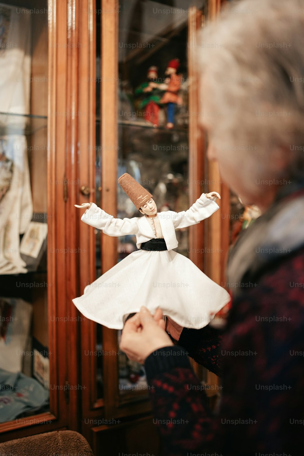 a woman holding a doll in front of a glass case