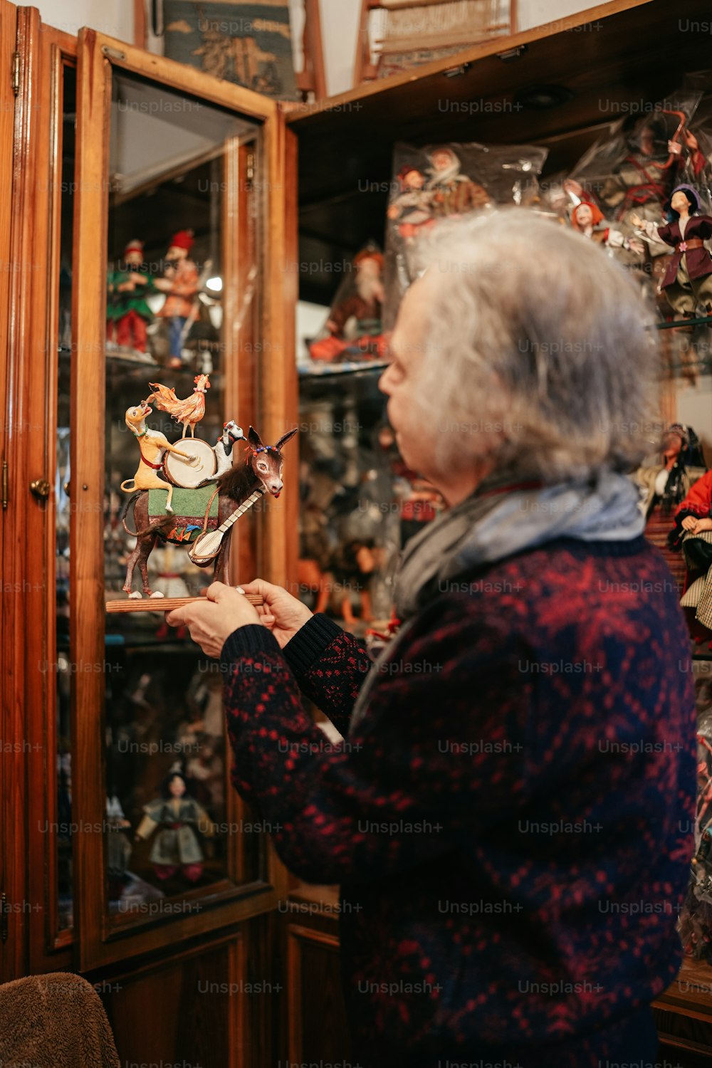 an older woman looking at a glass case with figurines on it