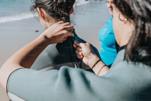 a woman sitting on top of a surfboard next to another woman