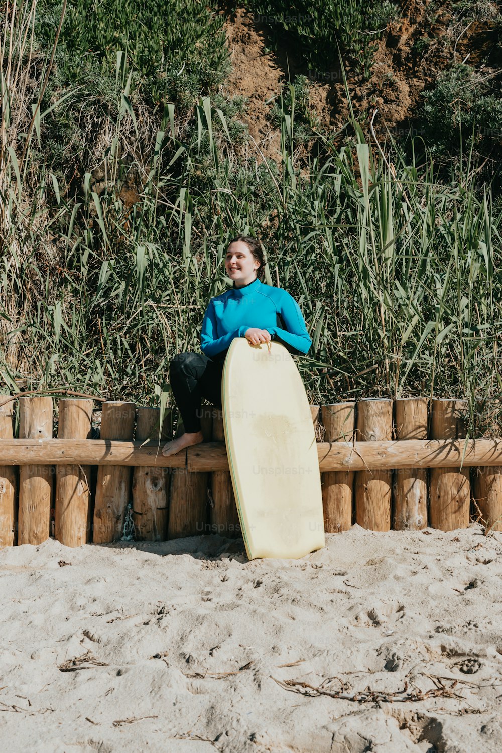 a man sitting on a wooden bench holding a surfboard