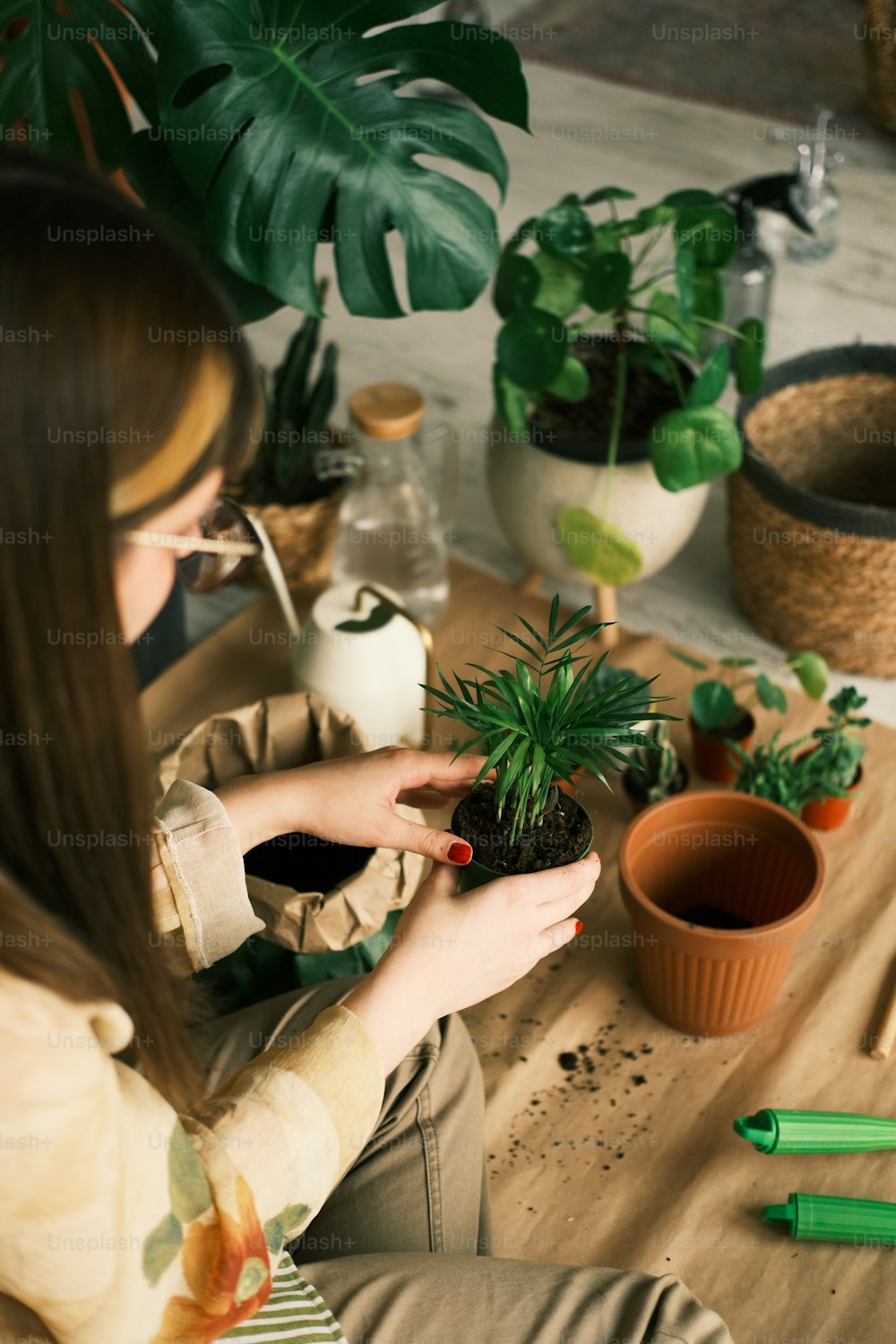 uma mulher sentada em uma mesa segurando um vaso de planta