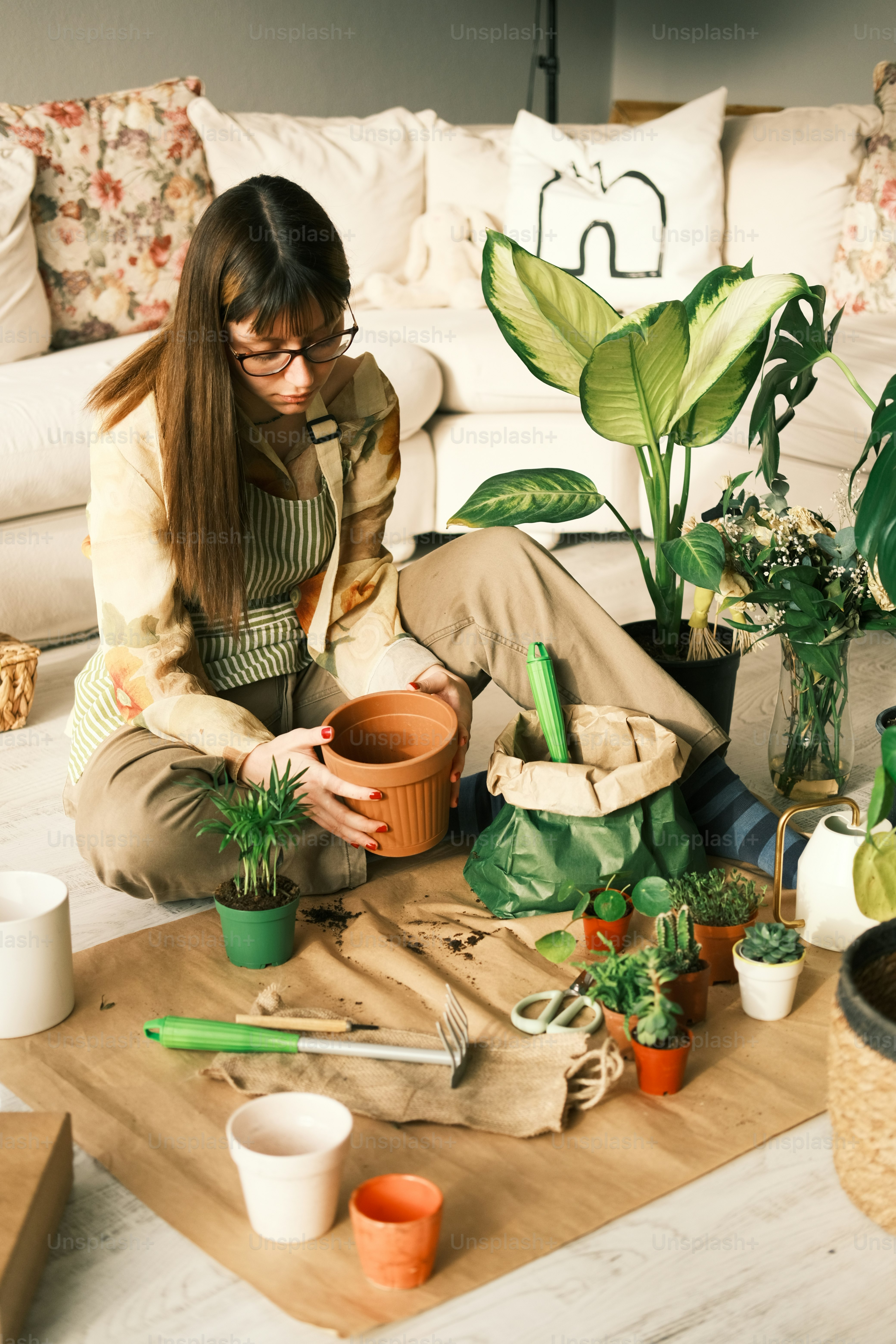 a woman sitting on the floor next to a potted plant