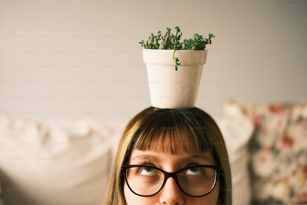 Una donna con gli occhiali e una pianta in testa
