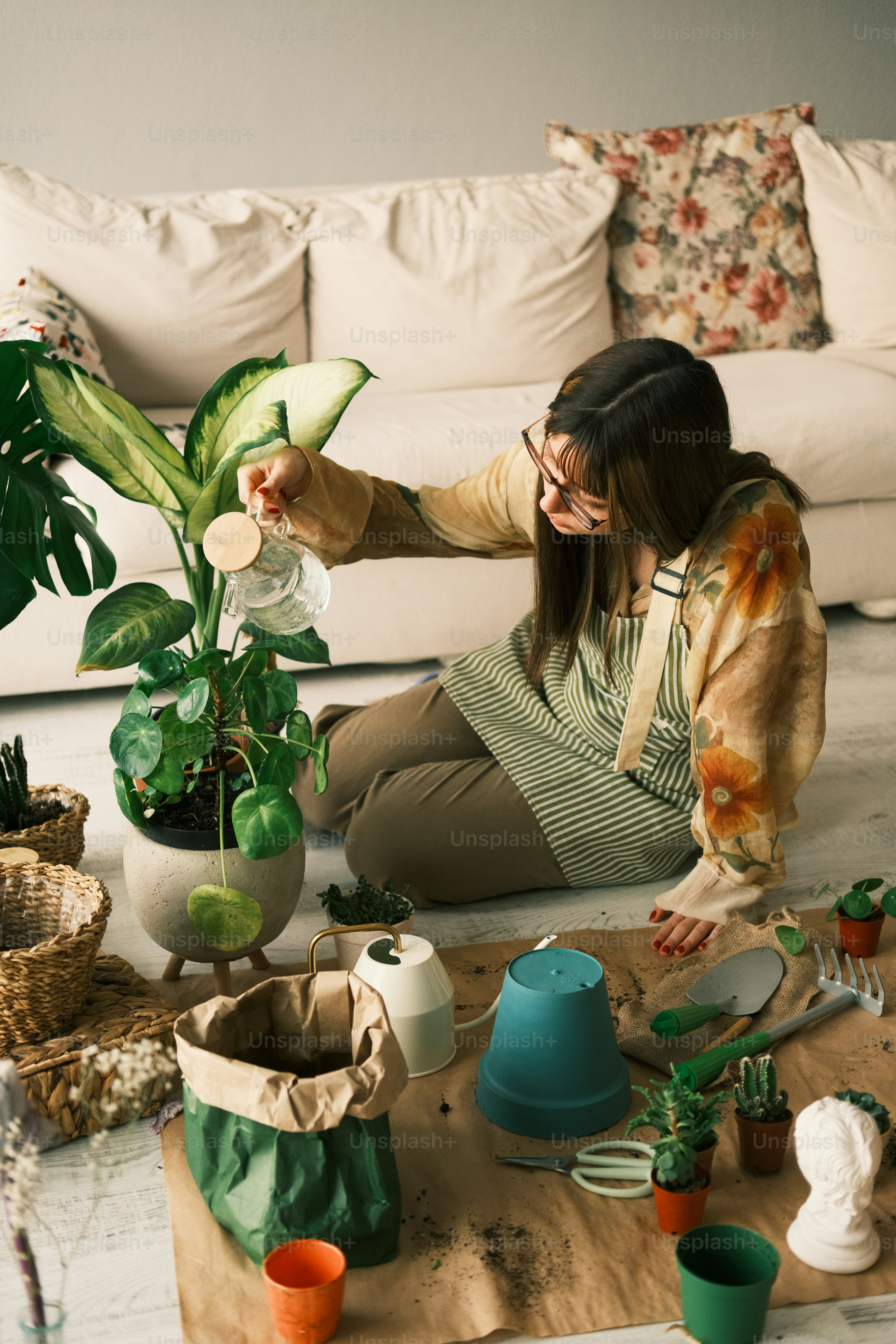a woman sitting on the floor next to a potted plant
