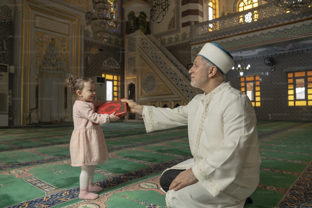 a little girl holding a red frisbee next to a man