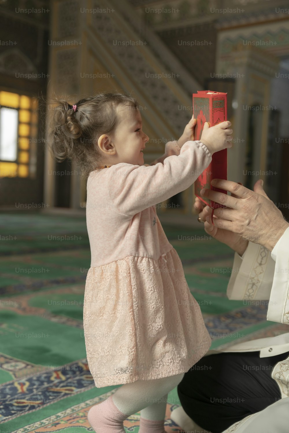 a little girl is playing with a red object