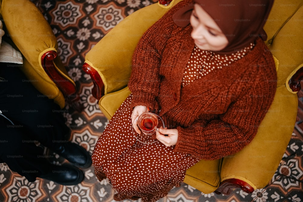 a woman sitting on a yellow chair holding a wine glass