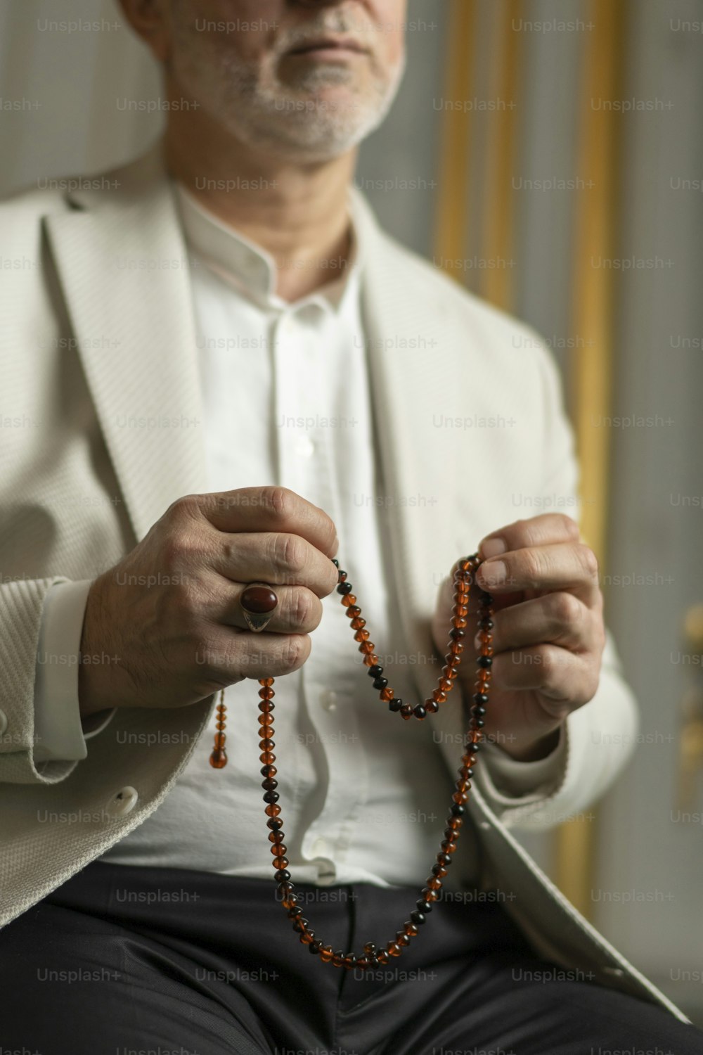 Un hombre con una chaqueta blanca sosteniendo un rosario