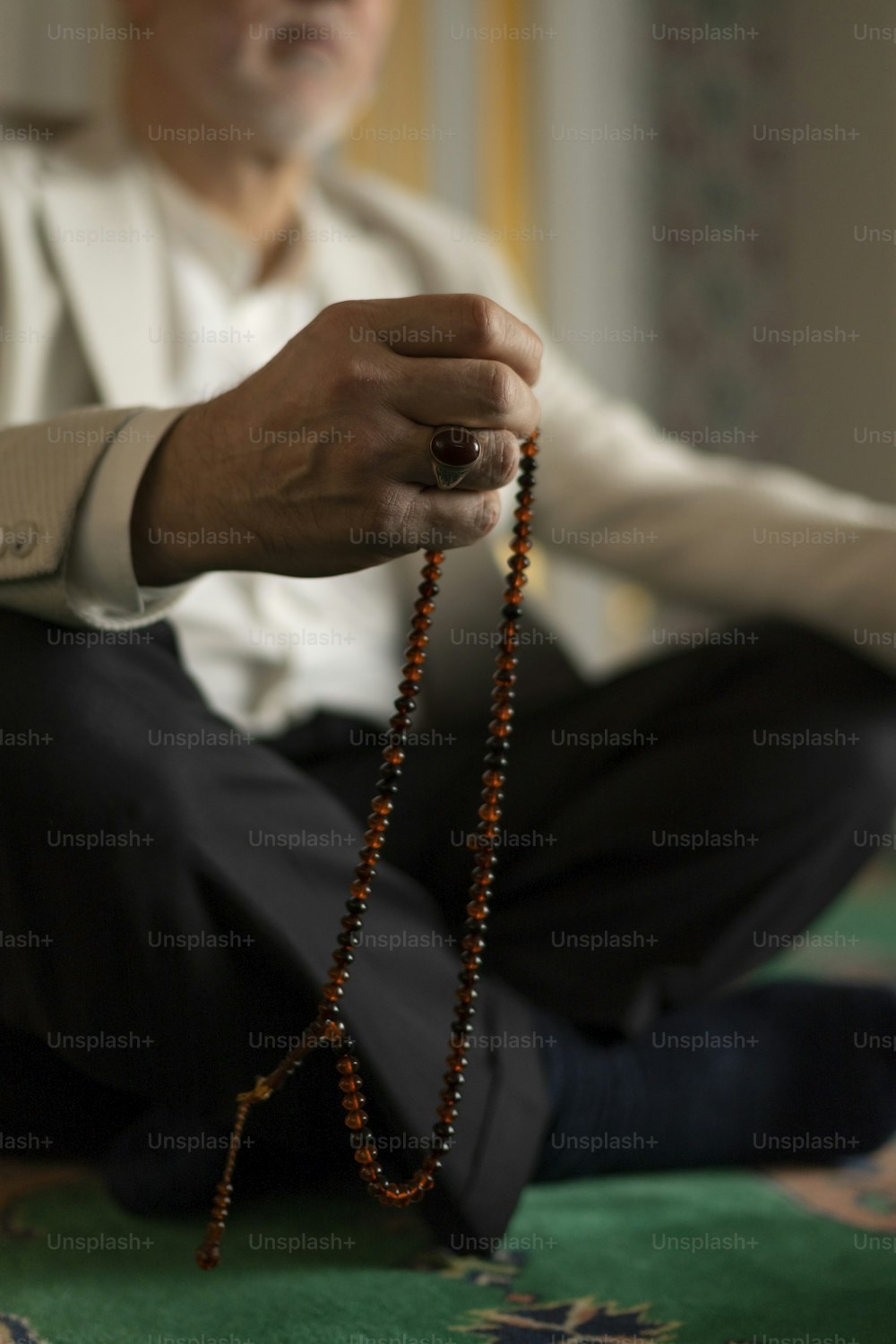 Un uomo seduto sul pavimento con in mano un rosario