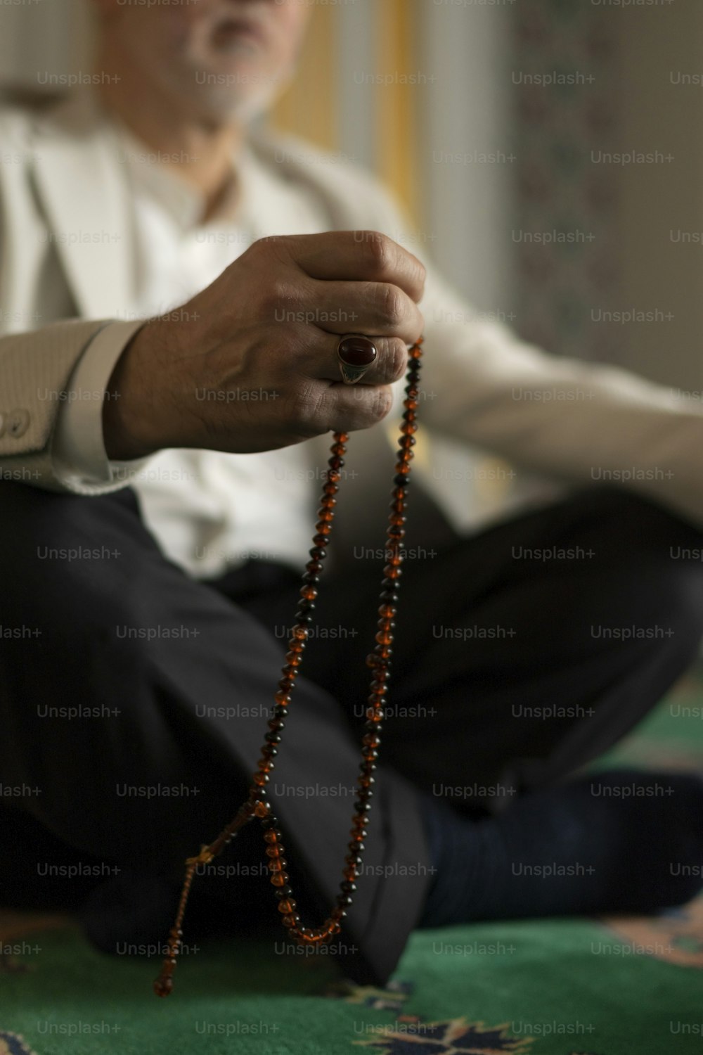 a man sitting on the floor holding a rosary