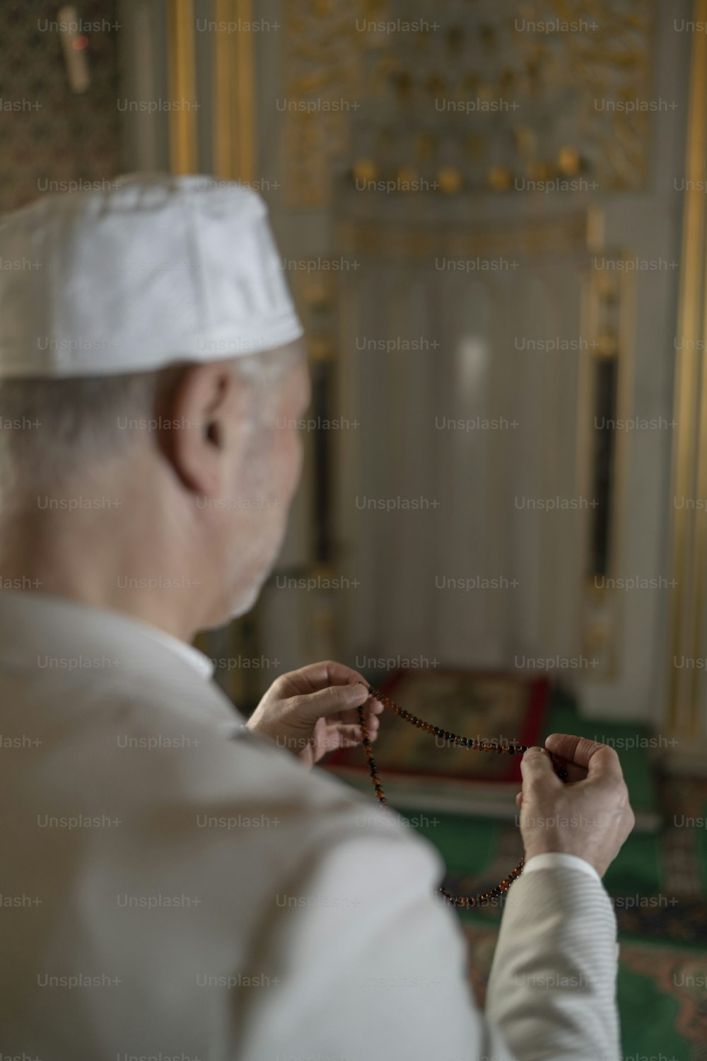 Un uomo con un cappello bianco tiene in mano un rosario