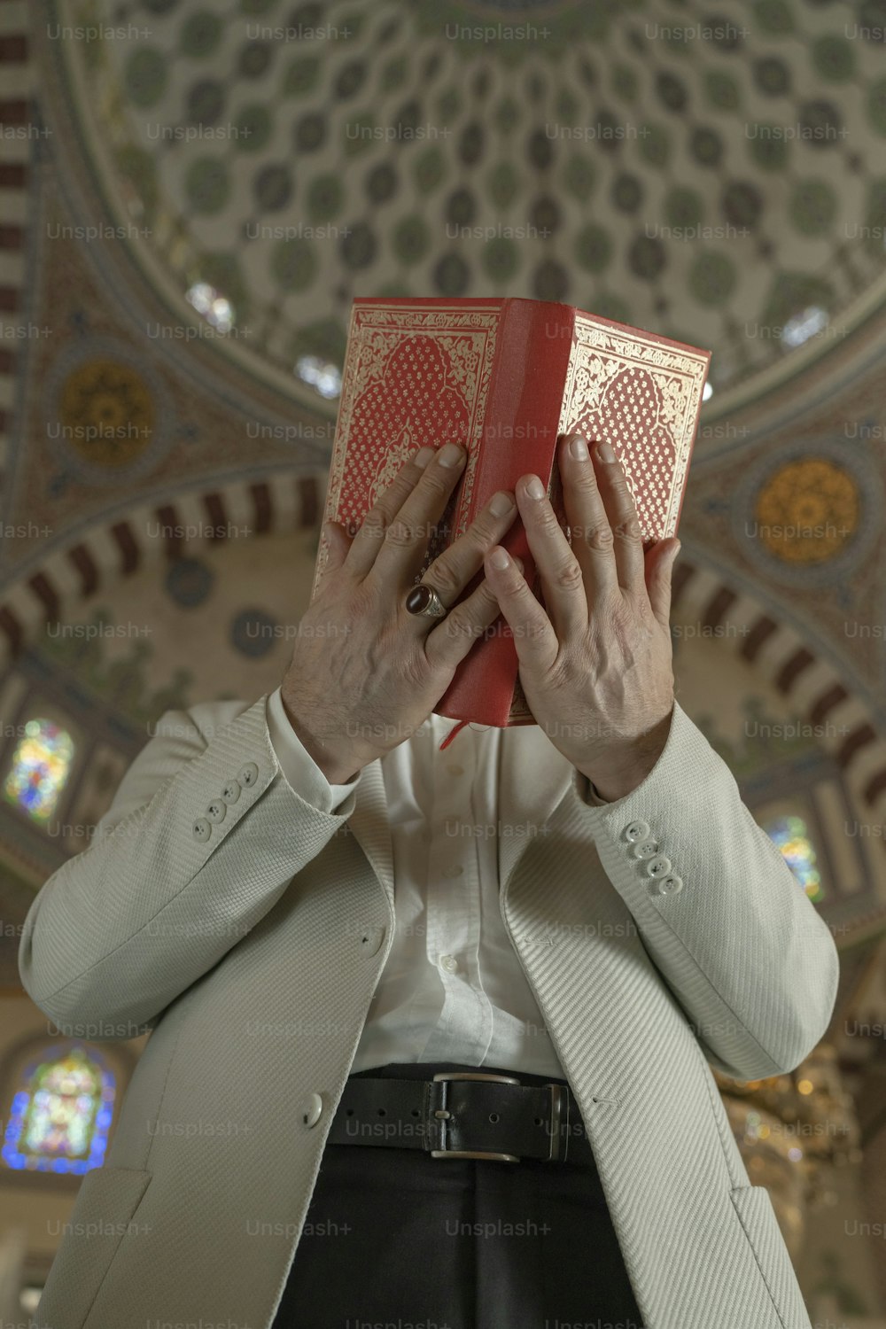 a man holding a red book in front of his face