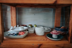 a wooden shelf filled with bowls and plates