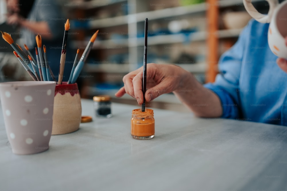 a person sitting at a table holding a paintbrush