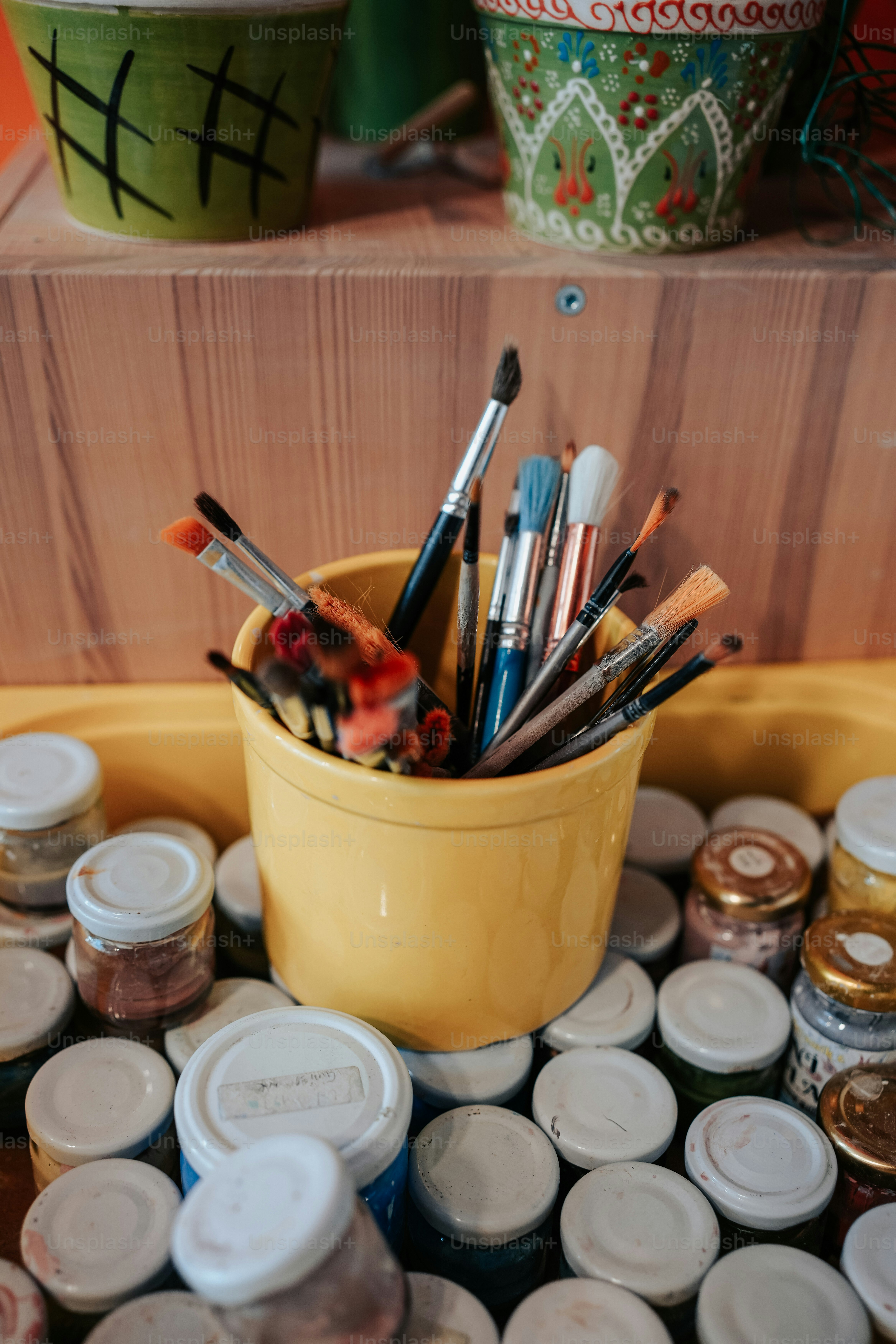 A yellow container filled with lots of paint brushes photo – Paint cans ...