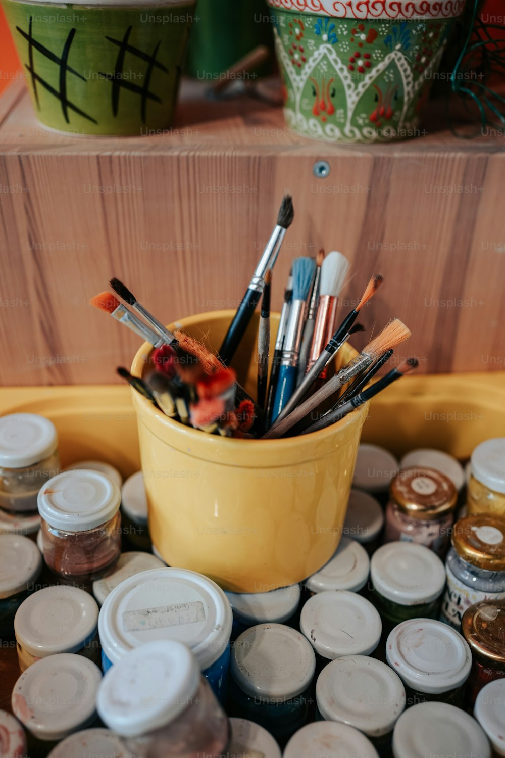 a yellow container filled with lots of paint brushes