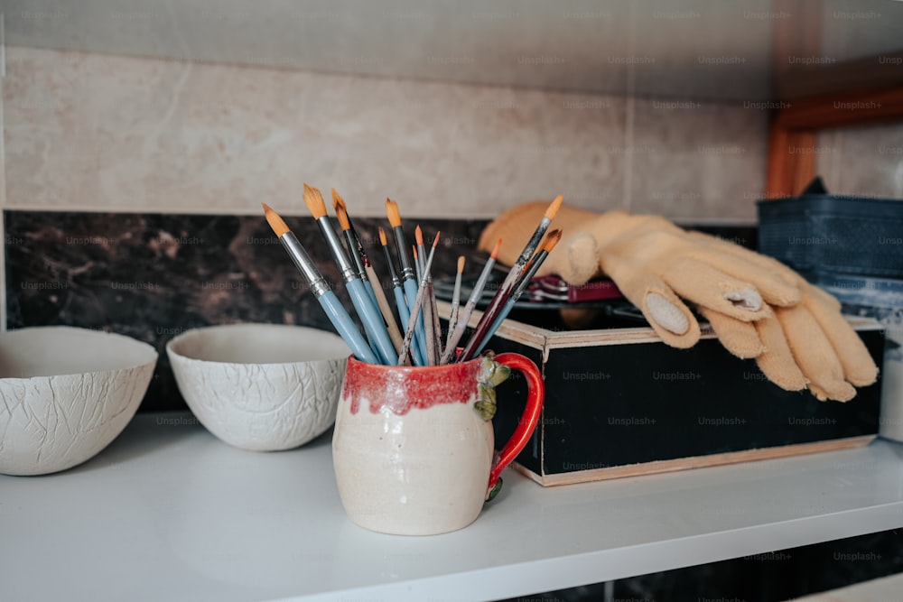 a person's hand reaching for a cup with paintbrushes in it