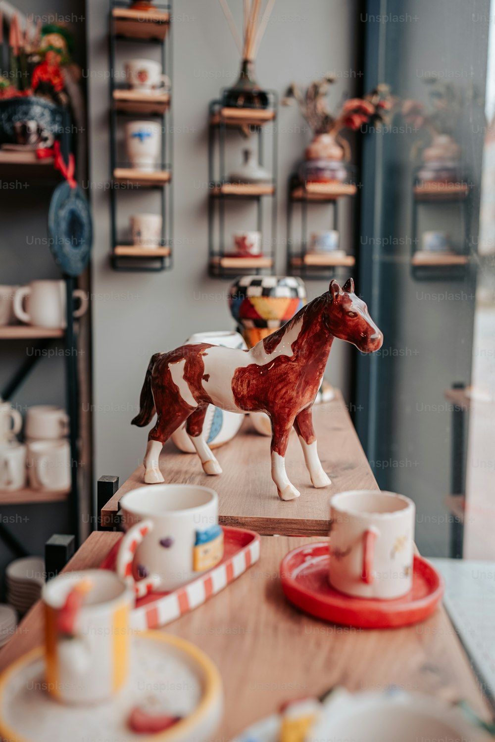 a wooden table topped with a cow figurine next to cups and saucers