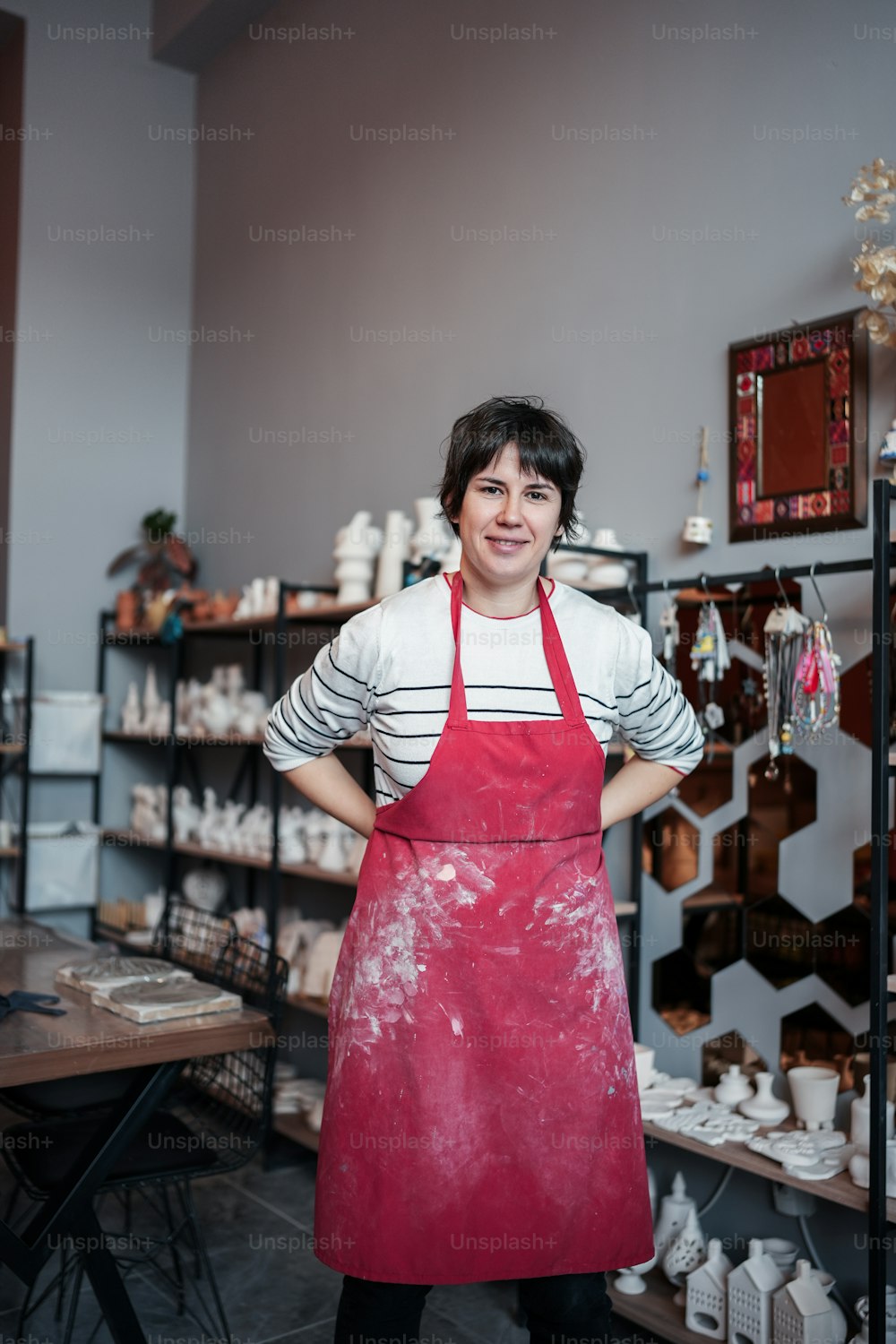 a woman in a red apron standing in a pottery shop