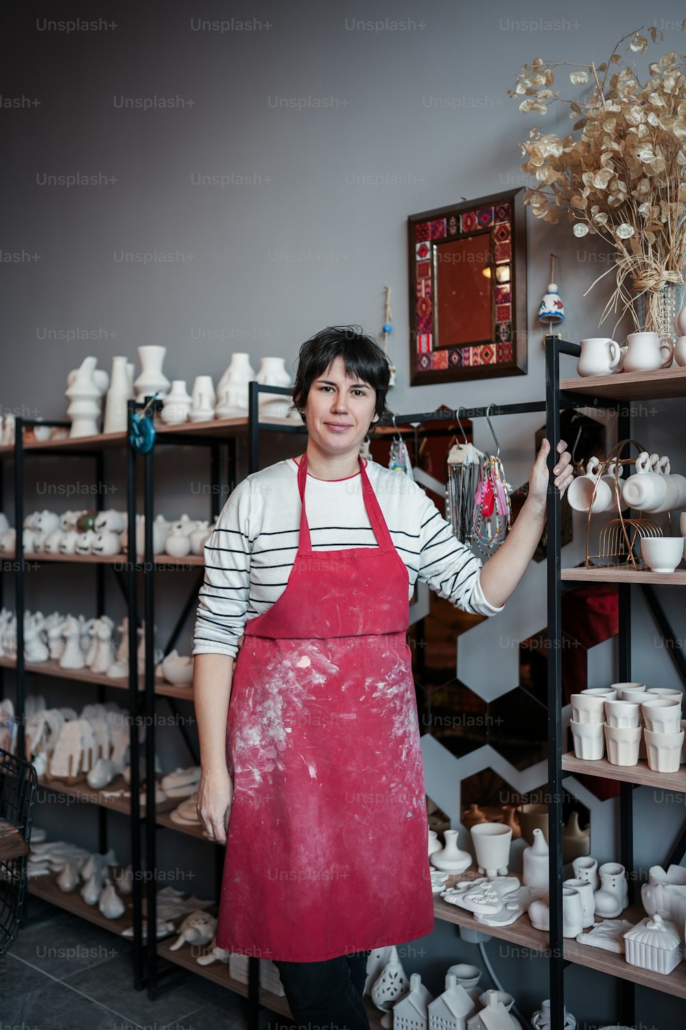 a woman standing in front of a shelf of pottery