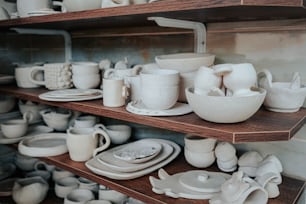 Un estante lleno de muchos platos blancos y tazas