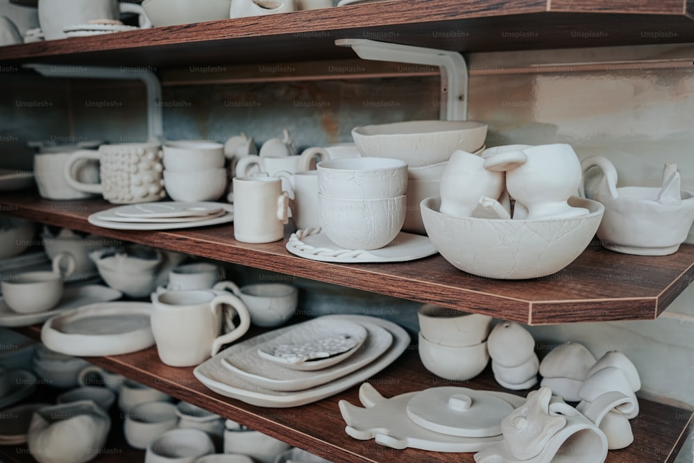 a shelf filled with lots of white dishes and cups