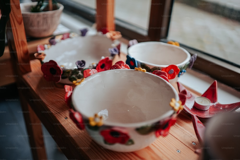 three white bowls with red and yellow flowers on them