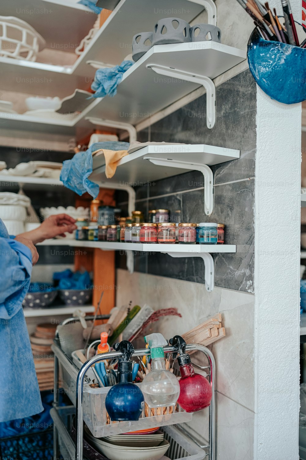 uma mulher em pé em uma cozinha ao lado de uma prateleira cheia de panelas e frigideiras