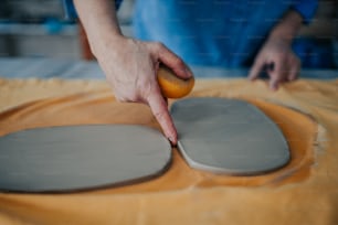 uma pessoa tocando um pedaço de cerâmica em uma mesa