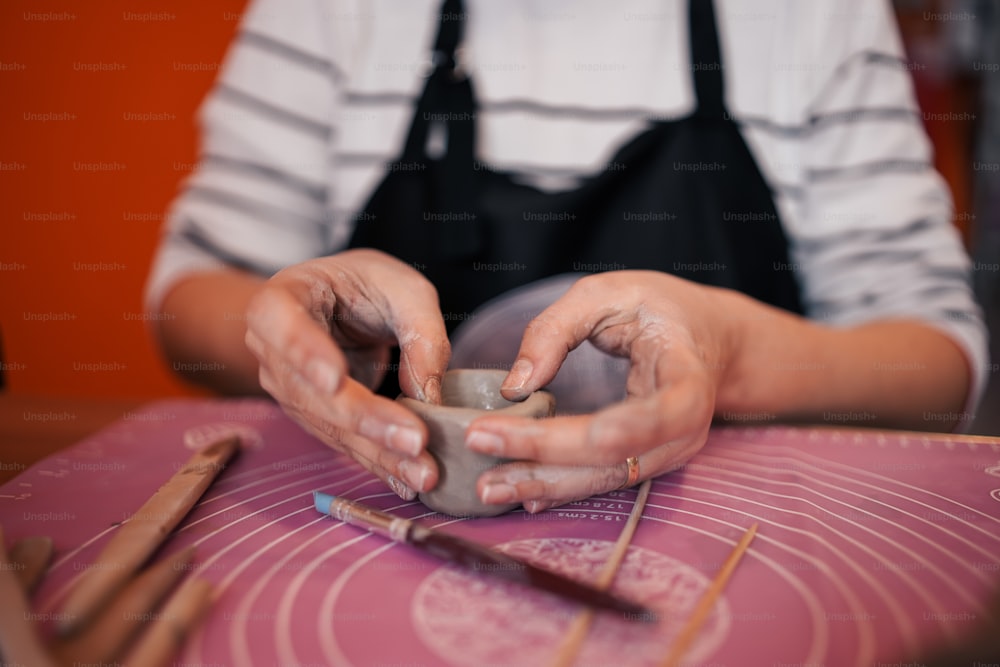 a woman is making a vase out of clay