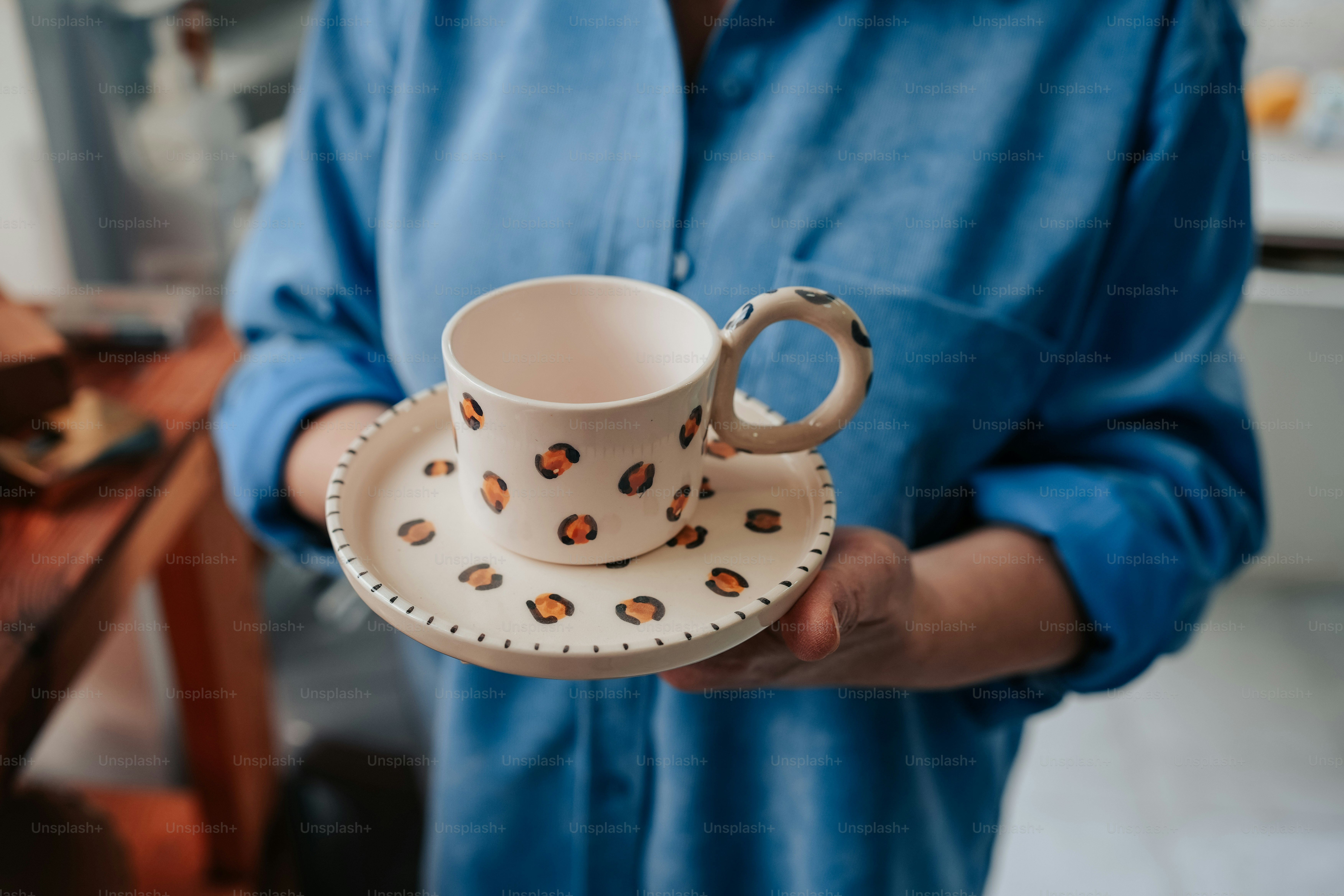 eine Person, die eine Kaffeetasse und eine Untertasse hält